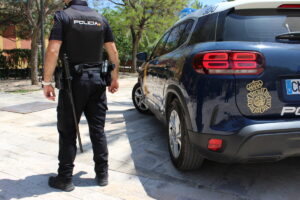 Agente de la Policía Nacional junto a su coche patrulla